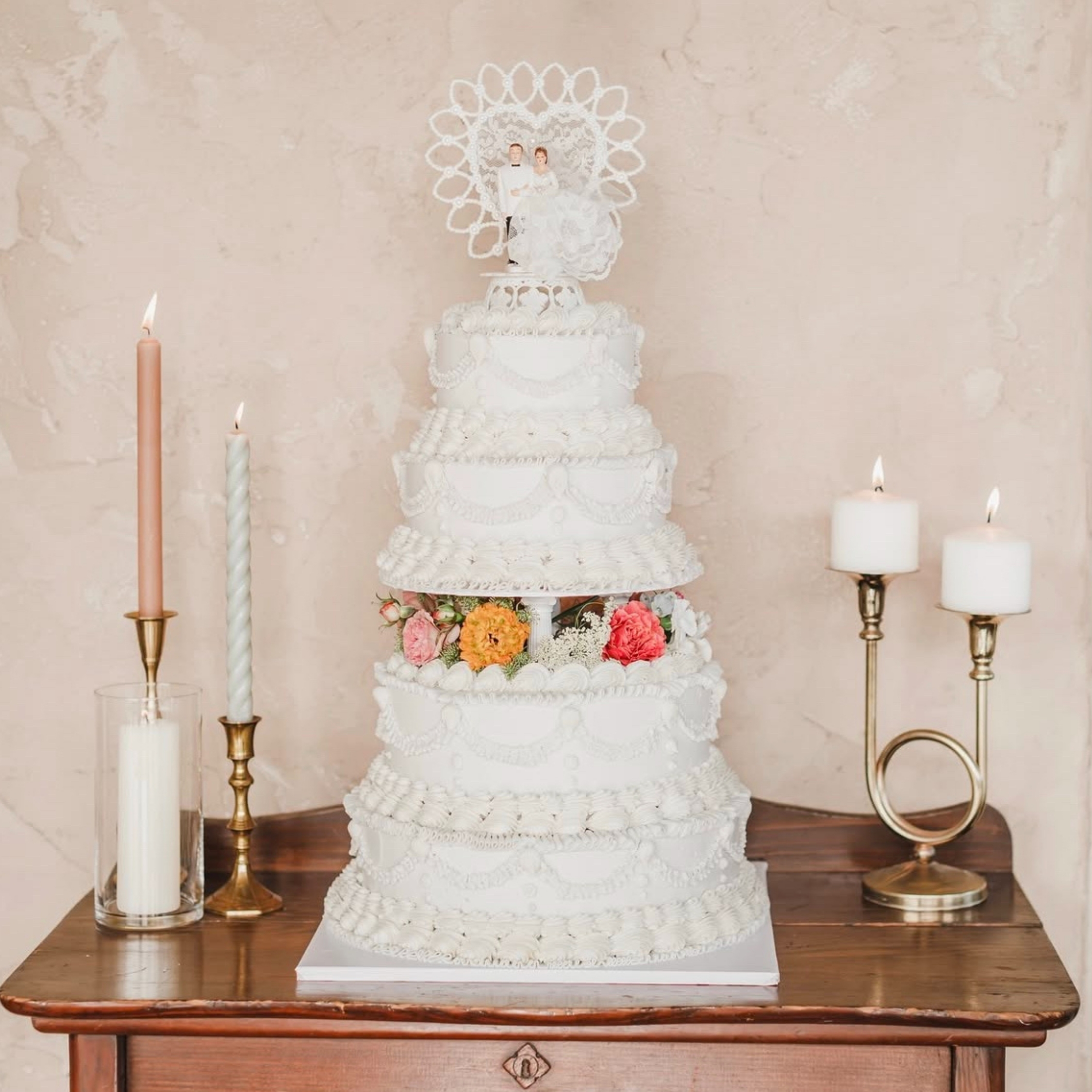 a four tier wedding cake with flowers and a bride and groom topper