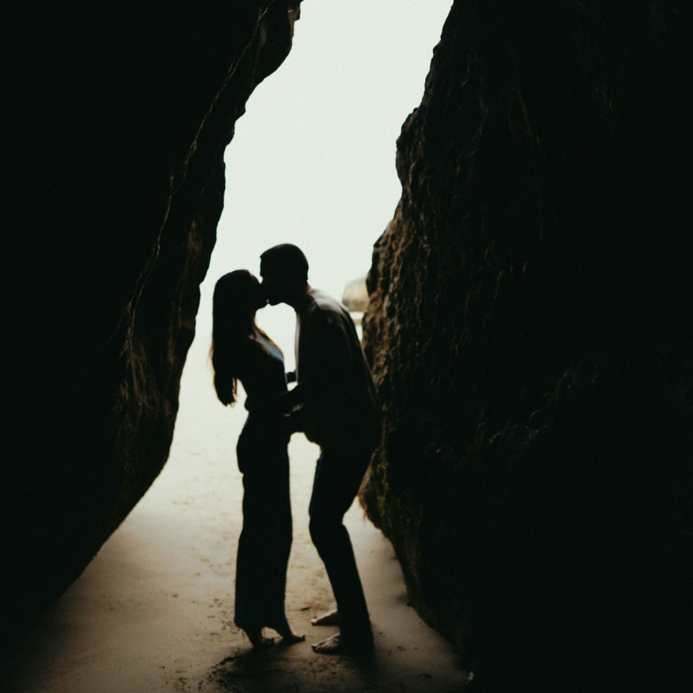 newlyweds kissing in a cave on the beach